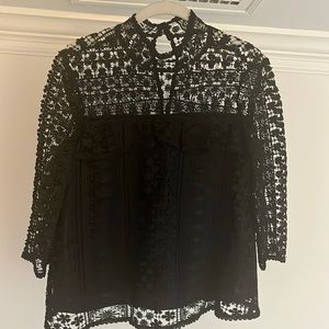 Knit/crocheted black long sleeve. Flower design with two buttons in back.